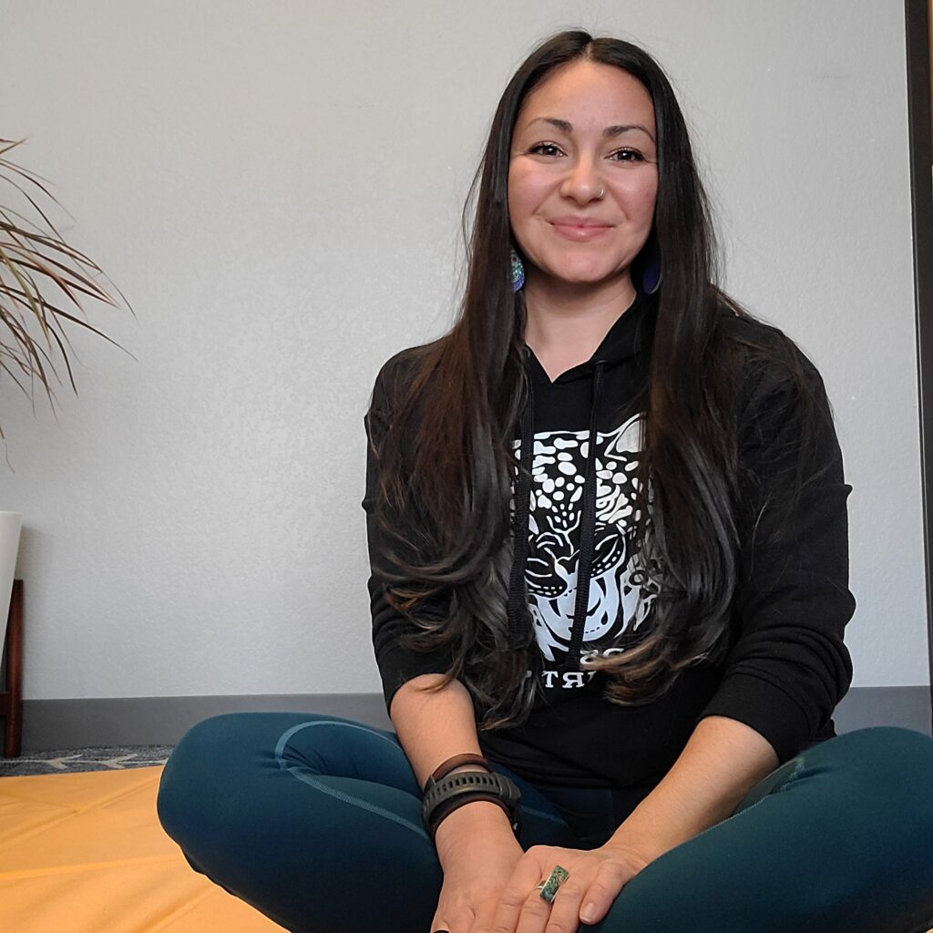 Brunette woman wearing a black hoodie and green leggings